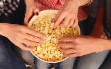 Close up top view photo of women's hands taking popcorn